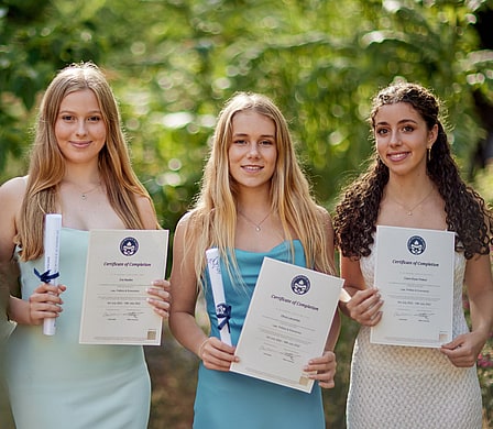 Students on an Oxford Summer School holding up their graduation certificates