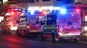Image shows three Australian ambulances with their lights flashing. 