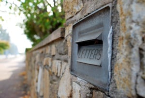 Image shows an old-fashioned embossed letterbox set into a wall.