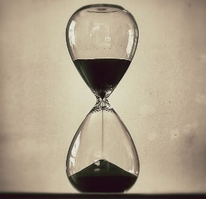 Image shows sand falling through an hourglass.