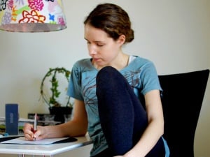 Image shows a student sitting at a desk, writing.