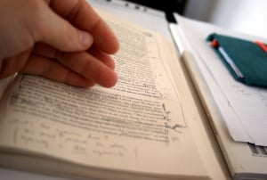 Image shows a student looking at a heavily annotated book.