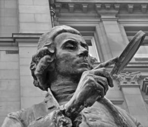 Image shows a statue with a magnifying glass.