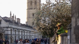Image shows Magdalen College on May Morning, with a crowd in the street and people dressed in green.