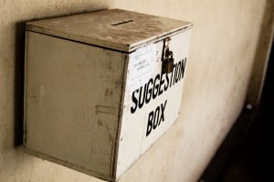Image shows a wooden box marked "Suggestion Box."