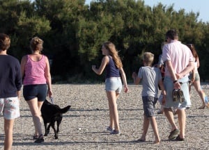 Image shows a family walking together on the beach.