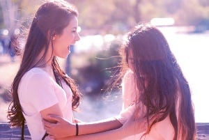 Image shows two teenage girls laughing together.