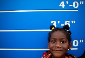 Image shows a girl standing against a height chart.