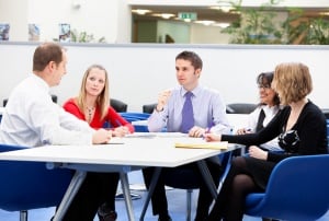 Image shows a group of people having a meeting. 
