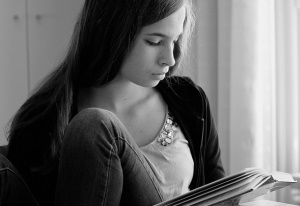 Image shows a young woman reading.