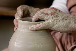 Image shows someone making a vase on a potter's wheel. 