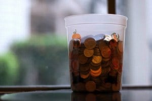 Image shows a jar full of small change. 