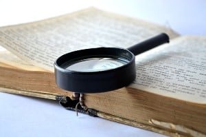 Image shows a magnifying glass on a book.