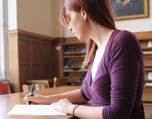 Image shows a student working in a library.