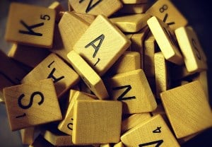 Image shows a disorderly pile of Scrabble tiles with various letters on them. 