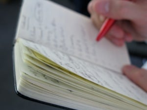 Image shows someone writing in a notebook.