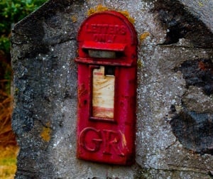 Image shows a red British postbox.